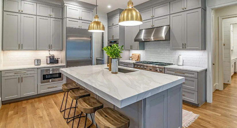 Cocina en concepto abierto con isla central iluminada por focos empotrados y lámparas suspendidas